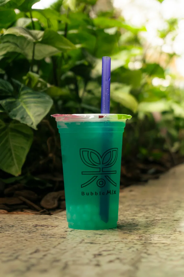 Copo Bubble Mix Tea verde em meio à vegetação